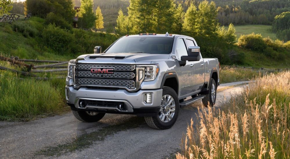 A white 2021 GMC Sierra 2500 HD driving on a dirt road.