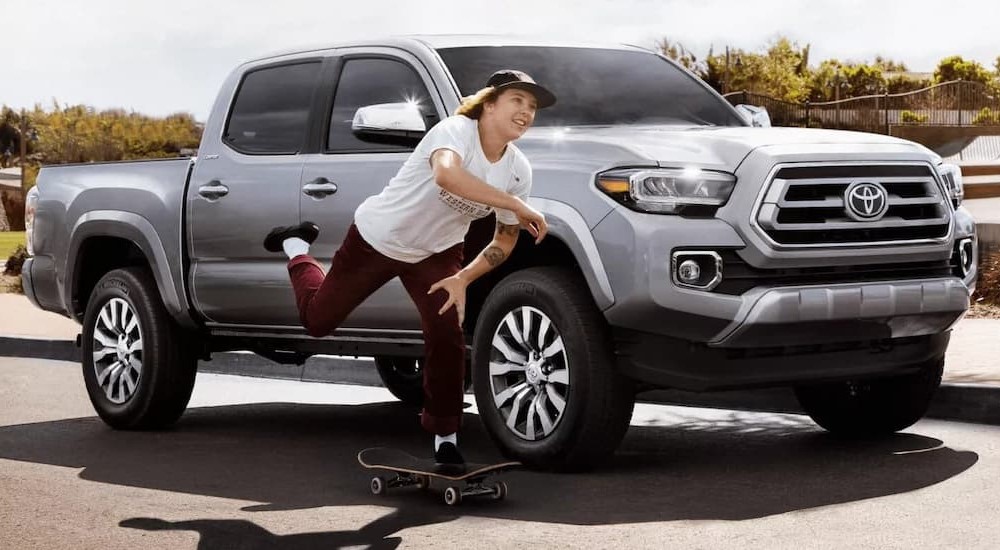 A person skateboarding near a silver 2022 Toyota Tacoma Limited.