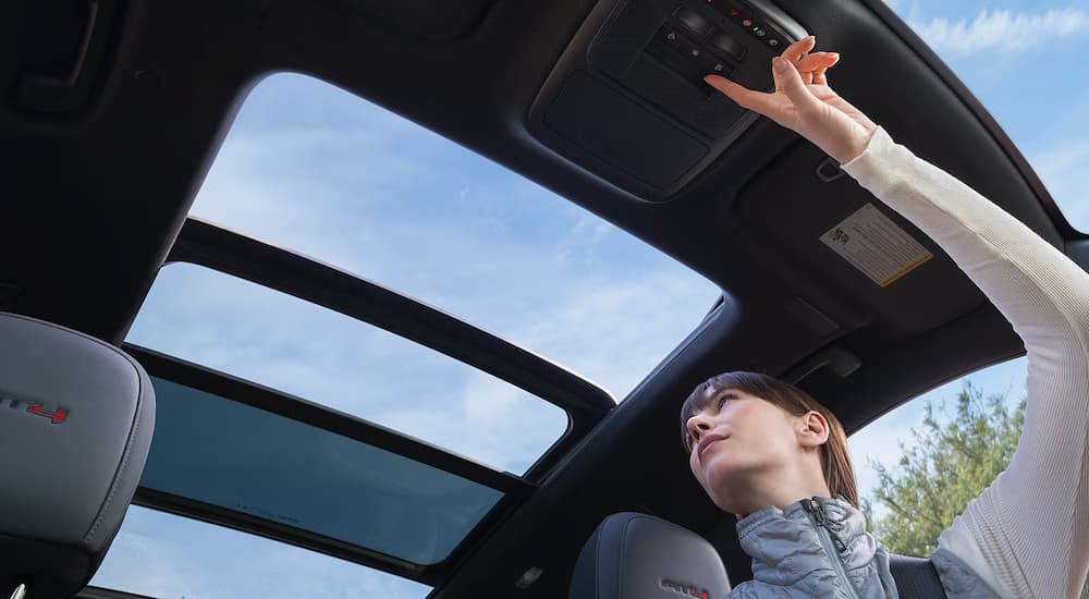 A woman using power moonroof on a 2025 GMC Acadia AT4 for sale