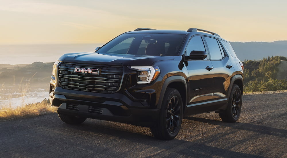 Black 2026 GMC Terrain for sale driving down an open dirt road.