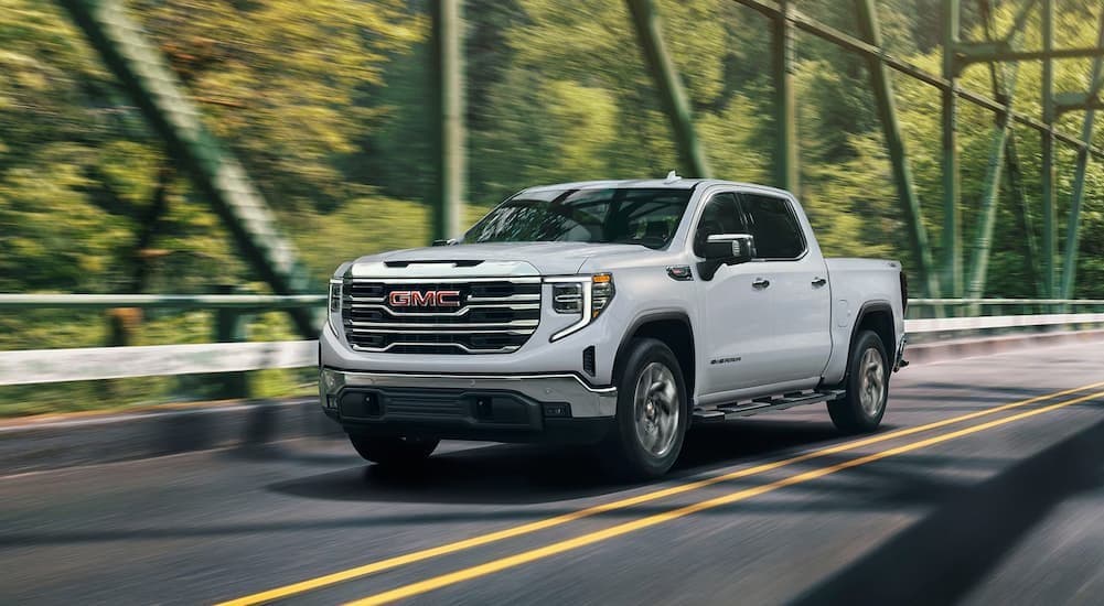 A white 2026 GMC Sierra 1500 driving on a bridge.
