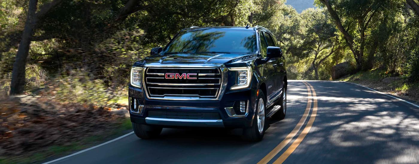 Black 2023 GMC Yukon driving down a forested road