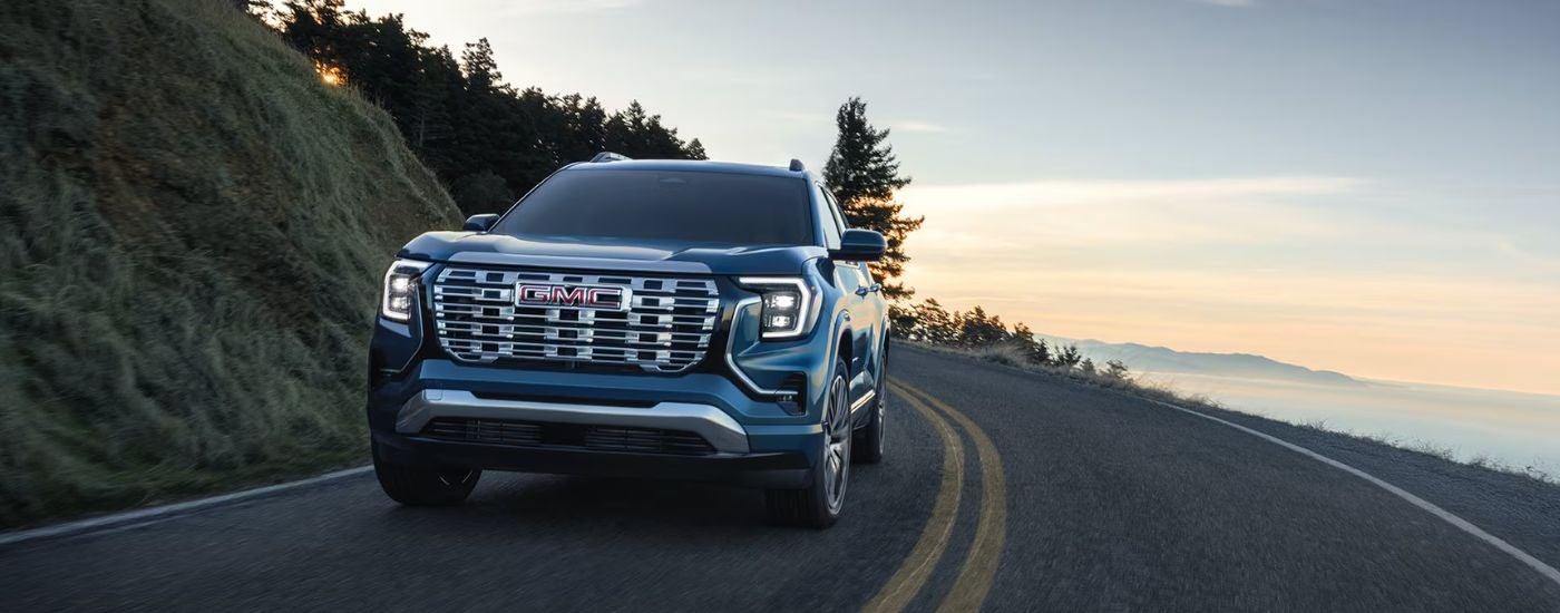 Blue 2026 GMC Terrain driving on a paved road.