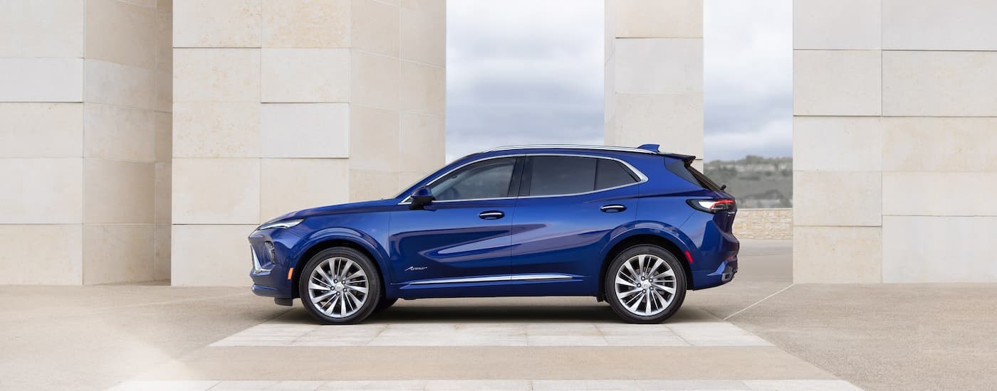 The side of a blue #2026 Buick Envision parked near a building.