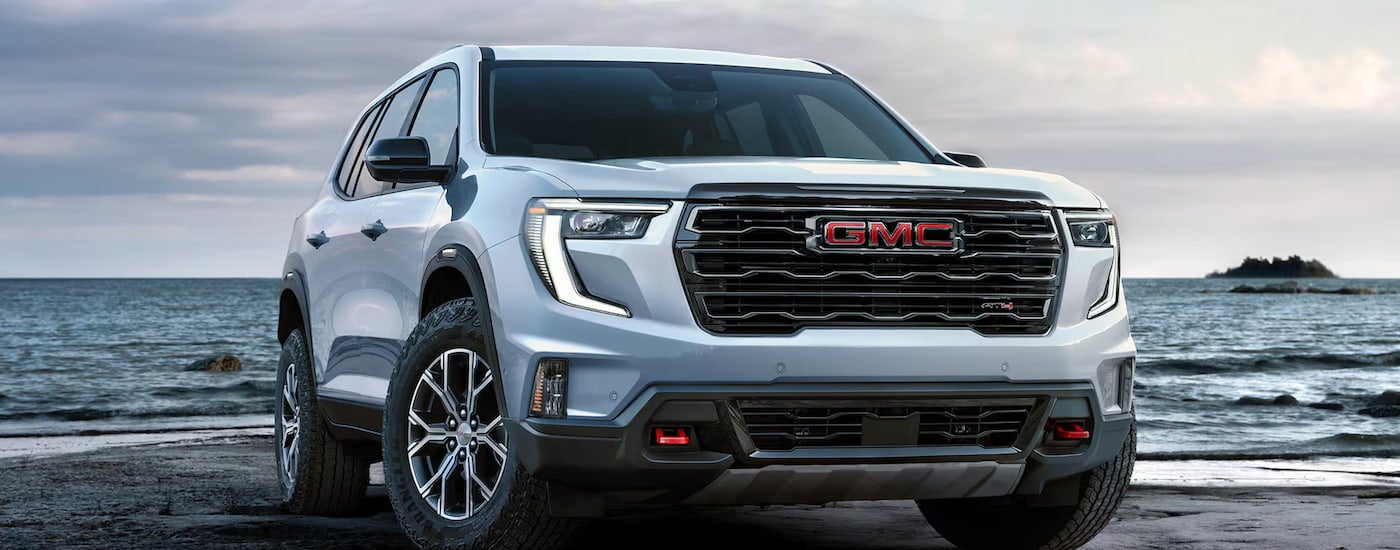 White 2026 GMC Acadia parked by a lake.