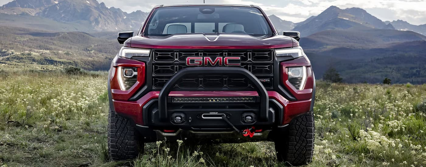 Front of a red 2026 GMC Canyon parked in a grassy field