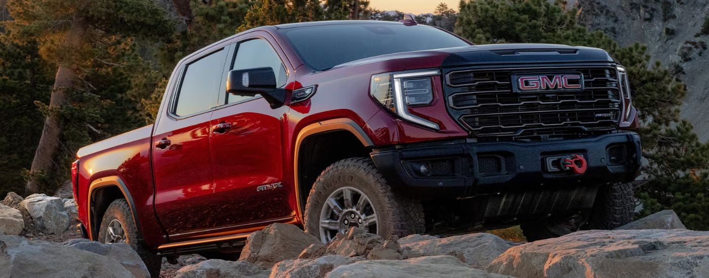 Red 2026 GMC Sierra 1500 driving up rocks. 
