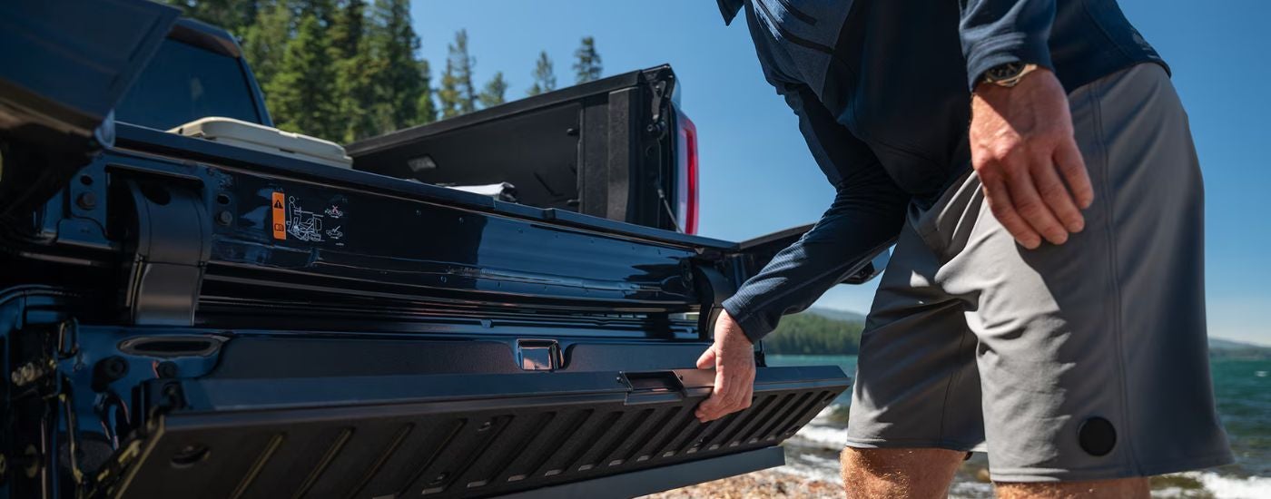 A man operating the Multi-Pro Tailgate on a black 2026 GMC Sierra 1500.