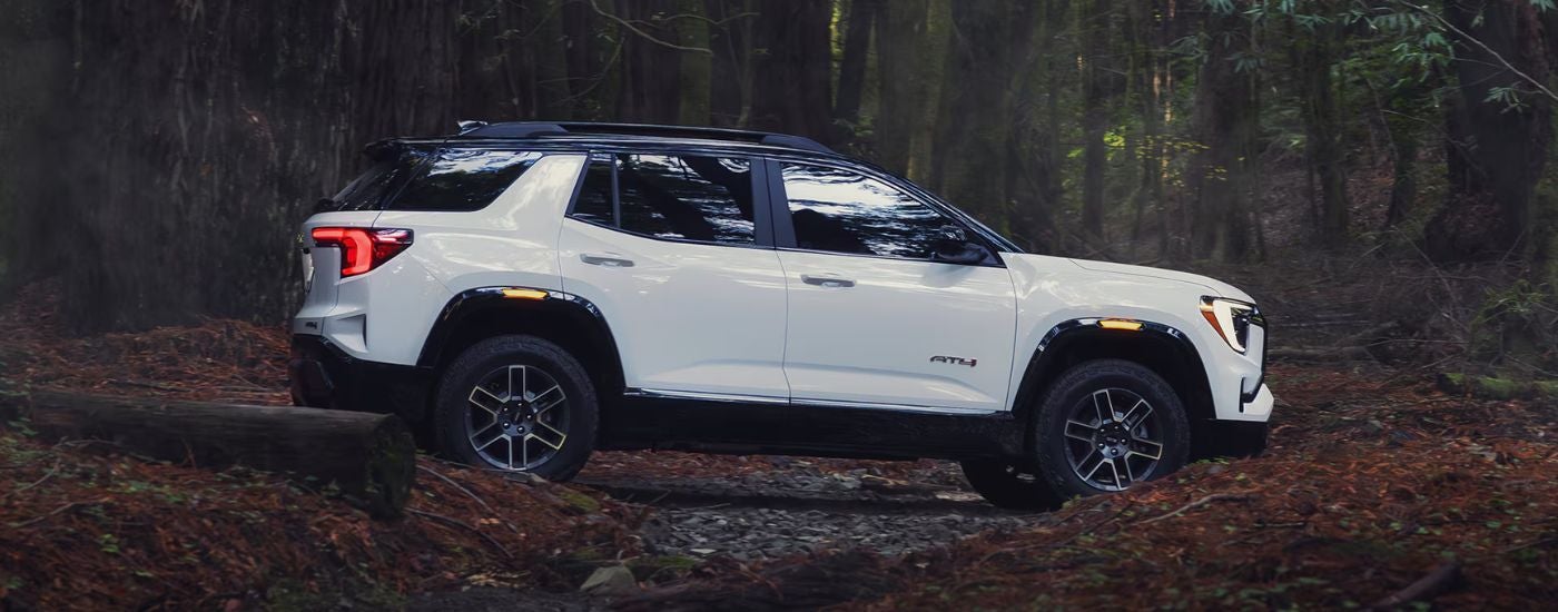 White 2026 GMC Terrain AT4 from the side in a forest.