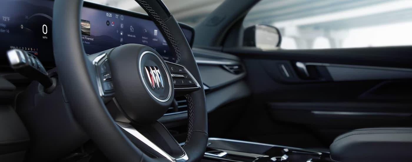 A close up of the steering wheel and center console in a 2025 Buick Enclave.