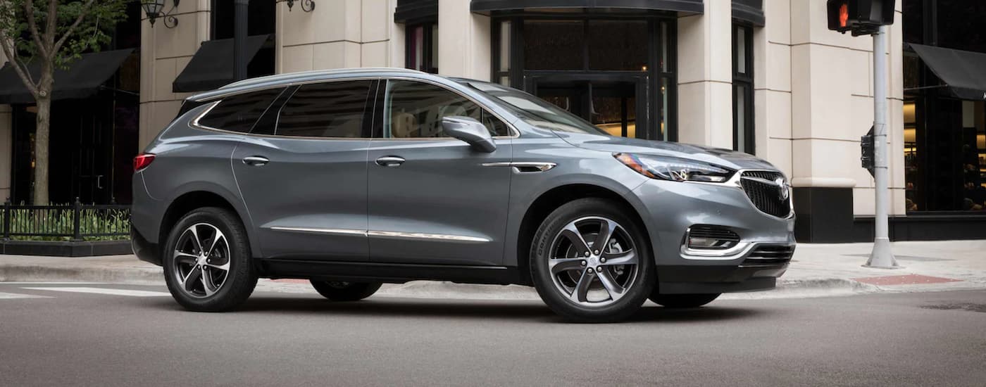 A grey 2021 Buick Enclave driving through an intersection in a city.