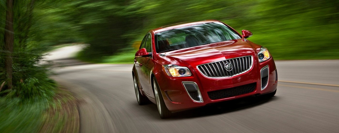 A red 2013 Buick Regal GS is driving to look at used cars for sale.